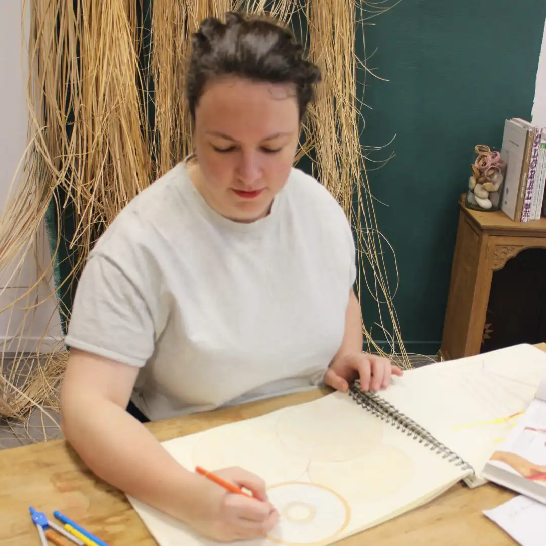 Inès dans son atelier en train de dessiner un futur projet